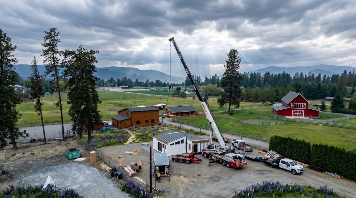 Crane setting an Elk Ridge home on its foundation beside a ranch