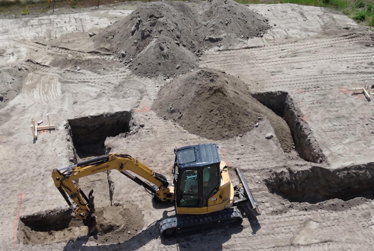 Excavator digging foundation footings on a home site